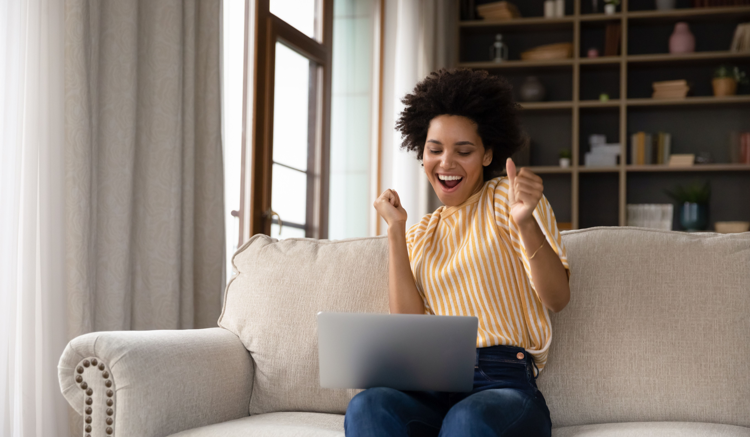 Woman ecstatic to be opening a high-yield savings account at her computer